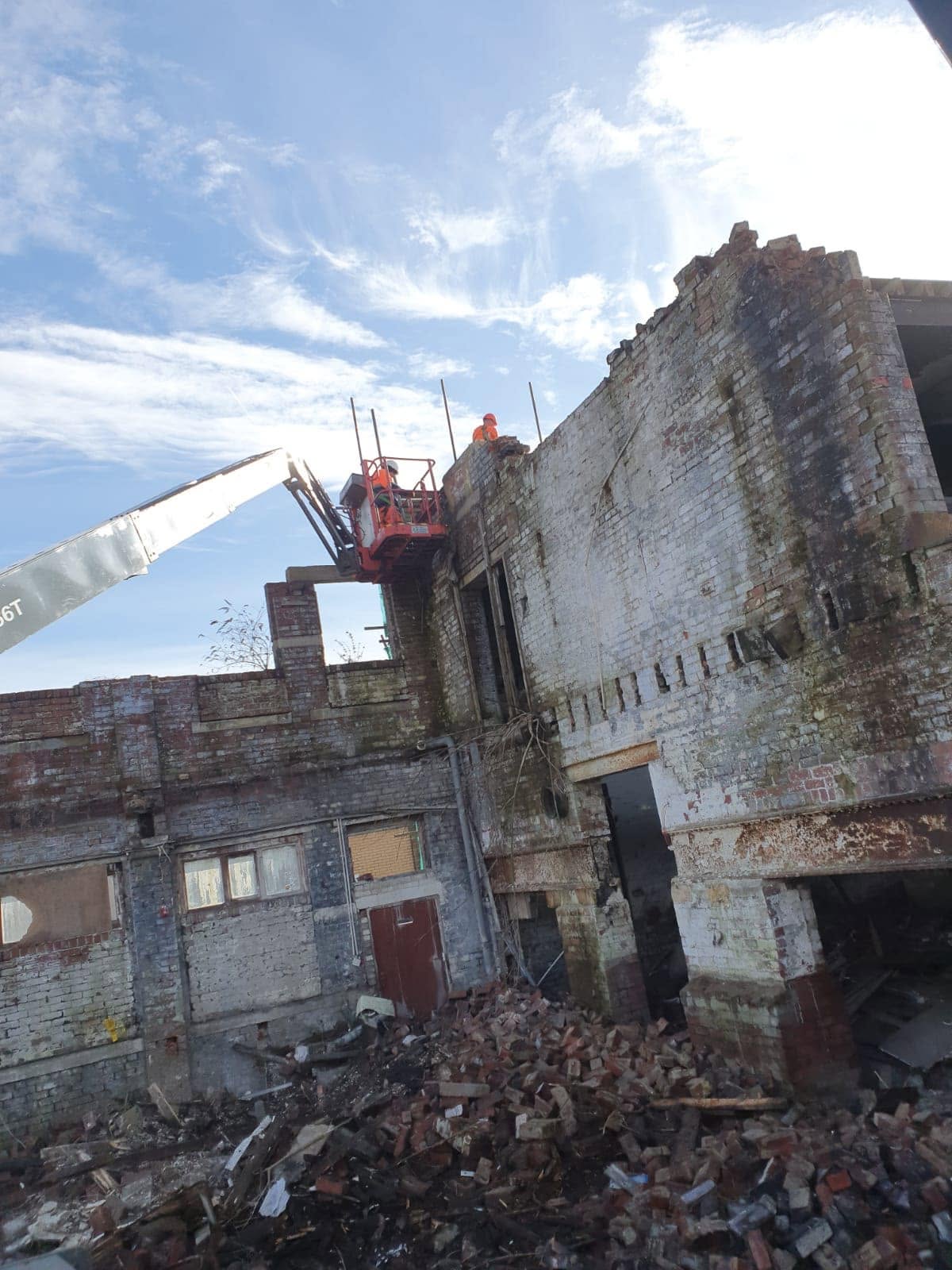 Mill building coming down by machine and by hand